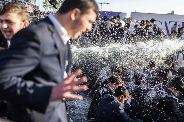 Israeli ultra-Orthodox Jews take cover from a water cannon spray during a protest against conscription by blocking the entrance to Jerusalem, on April 29, 2026. They oppose a change to the law on compulsory military service, from which the ultra-Orthodox community has traditionally been exempt. Under a provision established when the country was founded in 1948 – when the ultra-Orthodox community was small – men who dedicate themselves full-time to the study of Jewish sacred texts are effectively exempt. (Photo by ilia YEFIMOVICH / AFP) / 