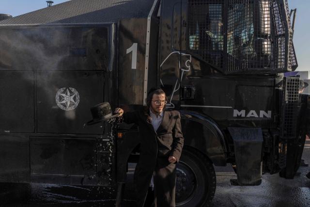 An Israeli ultra-Orthodox Jew reacts after being sprayed by a water cannon during a protest against conscription by blocking the entrance to Jerusalem, on April 29, 2026. They oppose a change to the law on compulsory military service, from which the ultra-Orthodox community has traditionally been exempt. Under a provision established when the country was founded in 1948 – when the ultra-Orthodox community was small – men who dedicate themselves full-time to the study of Jewish sacred texts are effectively exempt. (Photo by ilia YEFIMOVICH / AFP) / 