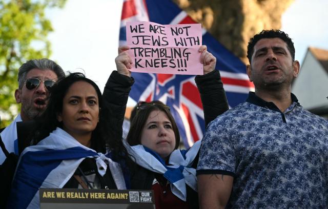 A person holds a banner reading 'We are not Jews with Trembling knees!' as they attend a protest in the Golders Green neighbourhood of north London, on April 29, 2026, following the stabbing of two people earlier today. Two people were stabbed on April 29 in north London, Jewish groups said, following a series of arson attacks targeting Jewish sites in the area. A man was arrested after he was seen running with a knife "attempting to stab Jewish members of the public", the Shomrim Jewish neighbourhood watch said on social media. (Photo by JUSTIN TALLIS / AFP)