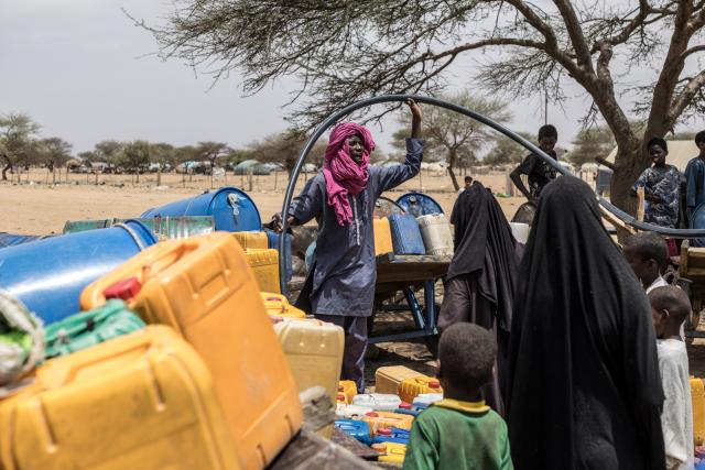 A man holds a water hose as he fills up jerry cans belonging to refugees and members of the community at a makeshift camp in Doueinkara, near the Mauritanian border with Mali, on April 29, 2026. Thousands of people have died in attacks in Mali since the jihadist turmoil erupted and tens of thousands of Malians have sought refuge in neighbouring countries, including Mauritania, in recent years. (Photo by PATRICK MEINHARDT / AFP)
