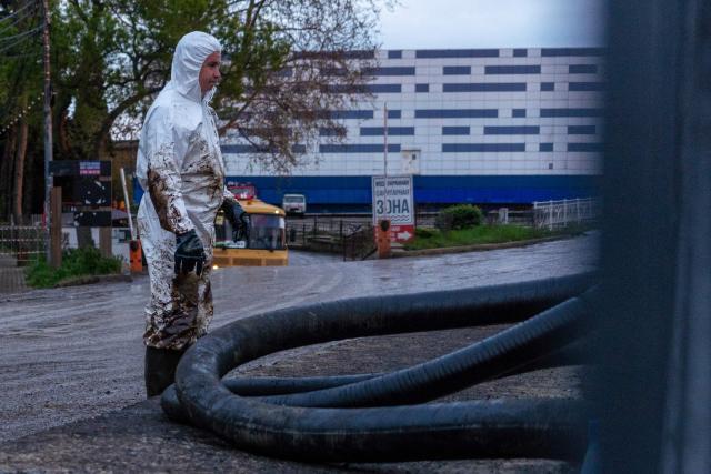 A worker stands next to a hose as he cleans the river of petroleum products following a spill caused by a recent drone attack on the Tuapse oil refinery in Tuapse, Krasnodar region on April 29, 2026, amid the ongoing Russian-Ukrainian conflict. (Photo by AFP)