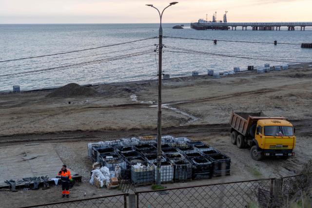 A worker stands next to containers of petroleum products recovered from the Black Sea following a spill caused by a recent drone attack on the Tuapse oil refinery in Tuapse, Krasnodar region on April 29, 2026, amid the ongoing Russian-Ukrainian conflict. (Photo by AFP)