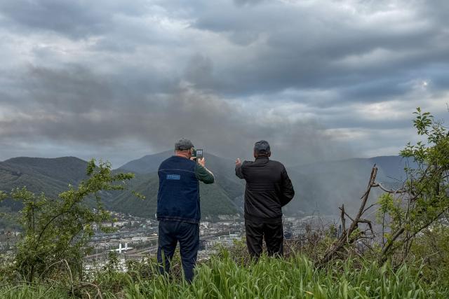Local residents observe smoke rising above buildings following a recent drone attack on the Tuapse oil refinery in Tuapse, Krasnodar region on April 29, 2026, amid the ongoing Russian-Ukrainian conflict. (Photo by AFP)