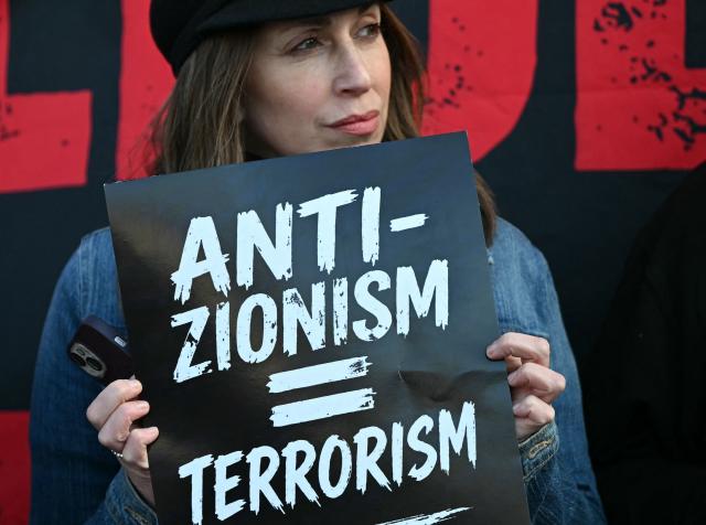 People hold banners reading 'Anti Zionism = Terrorism' as they attend a protest in the Golders Green neighbourhood of north London, on April 29, 2026, following the stabbing of two people earlier today. Two people were stabbed on April 29 in north London, Jewish groups said, following a series of arson attacks targeting Jewish sites in the area. A man was arrested after he was seen running with a knife "attempting to stab Jewish members of the public", the Shomrim Jewish neighbourhood watch said on social media. (Photo by JUSTIN TALLIS / AFP)