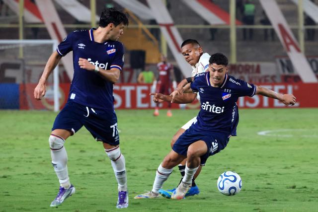 Nacional's midfielder #30 Baltasar Barcia and Universitario's Ecuadorian midfielder #27 Jose Carabali fight for the ball during the Copa Libertadores group stage football match between Peru's Universitario and Uruguay's Nacional at the Monumental "U" Marathon stadium in Lima on April 29, 2026. (Photo by Connie FRANCE / AFP)