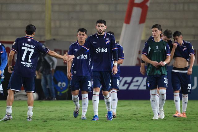 Nacional's defender #77 Nicolas Rodriguez shakes hands with teammate defender #02 Agustin Rogel (C) after losing the Copa Libertadores group stage football match between Peru's Universitario and Uruguay's Nacional at the Monumental "U" Marathon stadium in Lima on April 29, 2026. (Photo by Connie FRANCE / AFP)