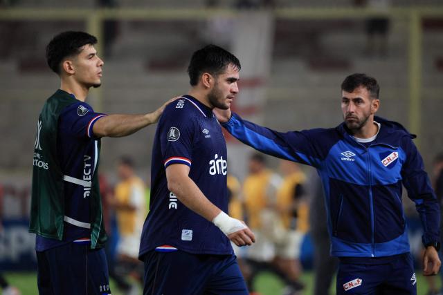 Nacional's forward #09 Maxi Gomez (C) is comforted by a teammate and staff after losing the Copa Libertadores group stage football match between Peru's Universitario and Uruguay's Nacional at the Monumental "U" Marathon stadium in Lima on April 29, 2026. (Photo by Connie FRANCE / AFP)