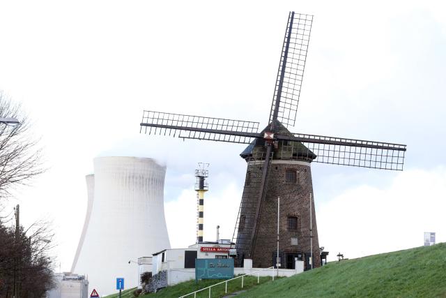 (FILES) This photograph taken on January 7, 2022 shows a windmill near the cooling towers of the Doel nuclear plant of Engie in Doel near Antwerp. Engie and the Belgian government have signed a letter of intent setting out the framework for negotiations regarding the French energy group’s sale of its nuclear operations to Belgium, the two parties announced on April 30, 2026. (Photo by Franзois WALSCHAERTS / AFP)