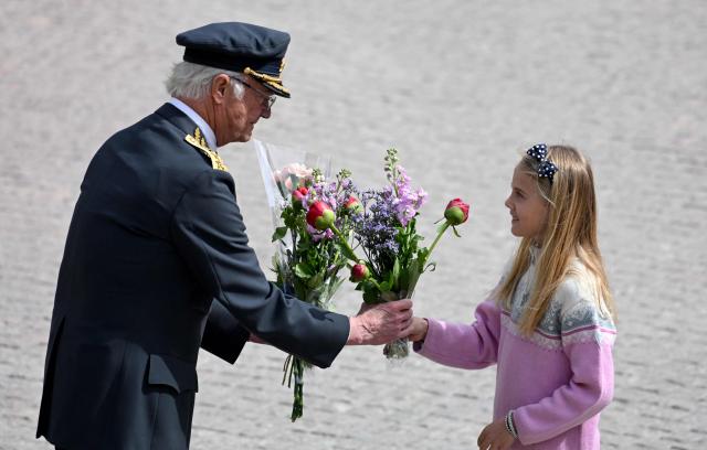 Sweden's King Carl XVI Gustaf is given flowers by a girl during the changing of the guard ceremony to pay tribute to the King at the Outer Courtyard of the Royal Palace in Stockholm, Sweden, on April 30, 2026, during celebrations to mark the 80th birthday of the King. (Photo by Jonathan Nackstrand / AFP)