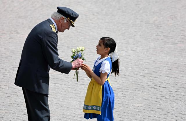 Sweden's King Carl XVI Gustaf is given flowers by a girl during the changing of the guard ceremony to pay tribute to the King at the Outer Courtyard of the Royal Palace in Stockholm, Sweden, on April 30, 2026, during celebrations to mark the 80th birthday of the King. (Photo by Jonathan Nackstrand / AFP)