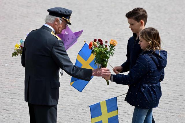 Sweden's King Carl XVI Gustaf is given flowers by children during the changing of the guard ceremony to pay tribute to the King at the Outer Courtyard of the Royal Palace in Stockholm, Sweden, on April 30, 2026, during celebrations to mark the 80th birthday of the King. (Photo by Jonathan Nackstrand / AFP)