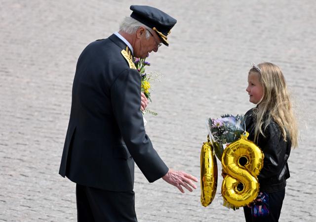 Sweden's King Carl XVI Gustaf is given flowers and balloons by a girl during the changing of the guard ceremony to pay tribute to the King at the Outer Courtyard of the Royal Palace in Stockholm, Sweden, on April 30, 2026, during celebrations to mark the 80th birthday of the King. (Photo by Jonathan Nackstrand / AFP)