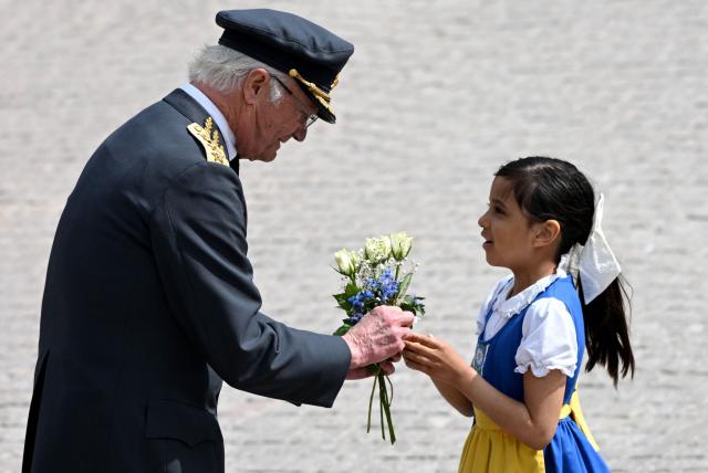 (ALTERNATIVE CROP) - Sweden's King Carl XVI Gustaf is given flowers by a girl during the changing of the guard ceremony to pay tribute to the King at the Outer Courtyard of the Royal Palace in Stockholm, Sweden, on April 30, 2026, during celebrations to mark the 80th birthday of the King. (Photo by Jonathan Nackstrand / AFP) / ALTERNATE CROP