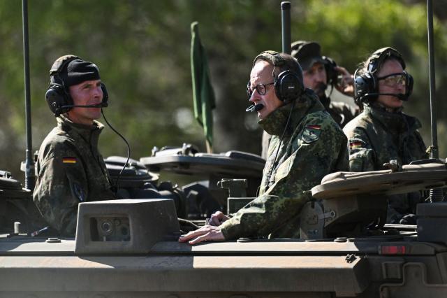 German Chancellor Friedrich Merz (C) and the Inspector of the Army Christian Freuding (L) sit on a GTK Boxer tank at the German army barracks in Munster, northern Germany, on April 30, 2026, as they visit the troops of the German Army. (Photo by Daniel Reinhardt / AFP)
