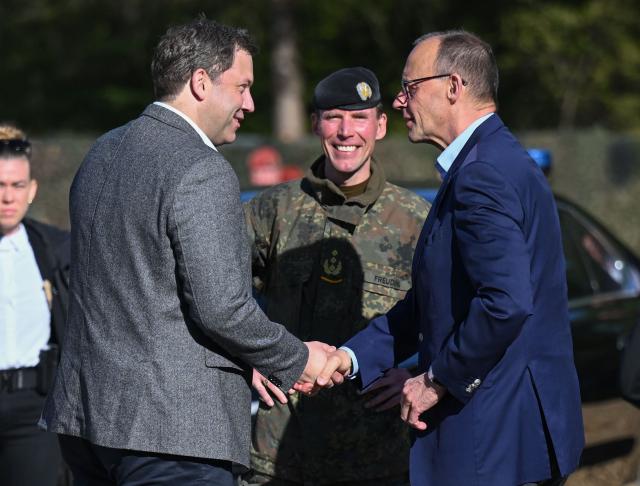 German Chancellor Friedrich Merz (R) and German Finance Minister and Vice Chancellor Lars Klingbeil (L) greet other under the etyes of the Inspector of the Army Christian Freuding (C) as they arrive at the German army barracks in Munster, northern Germany, on April 30, 2026, to visit the troops of the German Army. (Photo by Daniel Reinhardt / AFP) / ALTERNATIVE CROP