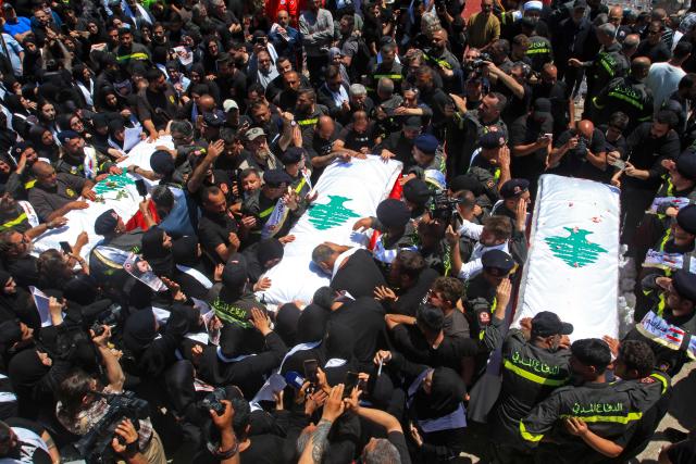 Mourners gather around the coffins of three Lebanese Civil Defense members who were killed in an Israeli airstrike on the town of Majdal Zoun, during their funeral in the southern city of Tyre on April 30, 2026. The Lebanese health ministry said Israeli strikes on April 28 killed eight people, including civil defence rescuers, and wounded two soldiers in the country's south, despite a fragile ceasefire. (Photo by Mahmoud ZAYYAT / AFP)