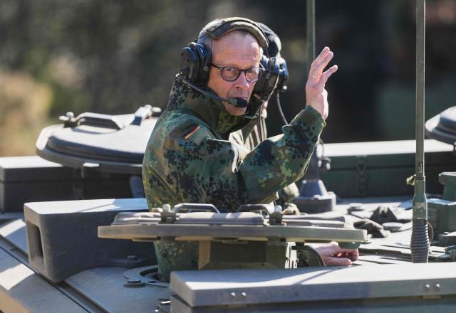 German Chancellor Friedrich Merz waves as he is driven in a GTK Boxer tank at the German army barracks in Munster, northern Germany, on April 30, 2026, as they visit the troops of the German Army.  (Photo by Markus Schreiber / POOL / AFP)