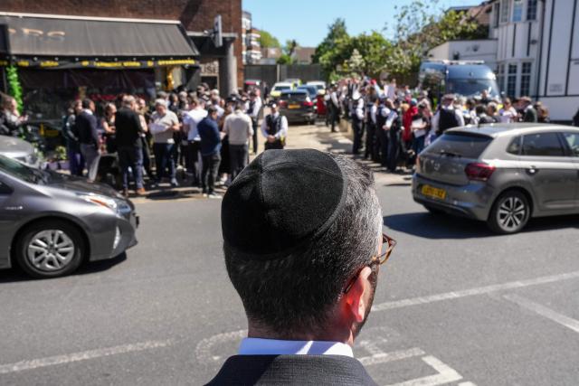 A local resident looks out as crowds gather during a visit by Britain's Prime Minister Keir Starmer to an ambulance centre servicing the Jewish community in the Golders Green neighbourhood of north London on April 30, 2026, the day after two men were stabbed in an attack. The UK government on April 30 announced extra money for security patrols outside synagogues and schools as community leaders accused it of failing to protect them, a day after the latest attack targeting the Jewish community. (Photo by CARLOS JASSO / AFP)