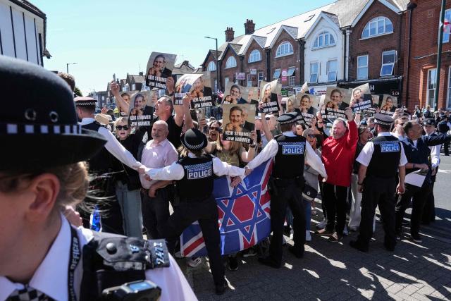 Police hold back protesters holding placards as a car (not pictured) carrying Britain's Prime Minister Keir Starmer passes by as he visits an ambulance centre servicing the Jewish community in the Golders Green neighbourhood of north London on April 30, 2026, the day after two men were stabbed in an attack. The UK government on April 30 announced extra money for security patrols outside synagogues and schools as community leaders accused it of failing to protect them, a day after the latest attack targeting the Jewish community. (Photo by CARLOS JASSO / AFP)
