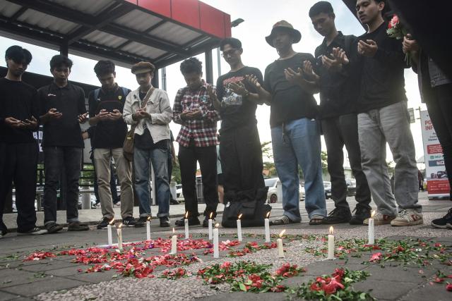 People take part in a flower-strewing ceremony to pray for the victims of a train collision, at Bekasi Timur Station in Bekasi, West Java, on April 30, 2026. The death toll from a train crash outside the Indonesian capital Jakarta rose to 16, all women, after an injured passenger passed away in hospital, officials said April 29. (Photo by Rezas / AFP)