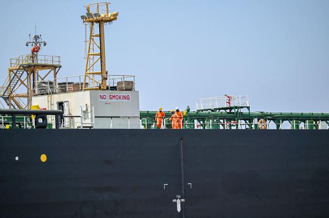 Sailors work on the deck of the Indian-flagged tanker Desh Garima, carrying crude oil that transited through the Strait of Hormuz, as it is docked at an offloading terminal along the coast in Mumbai on April 30, 2026. India, the world's third-largest oil buyer, normally sources about half of its crude through the Strait of Hormuz, a vital waterway that has seen only a trickle of traffic since the United States and Israel launched attacks on Iran on February 28. (Photo by Punit PARANJPE / AFP)