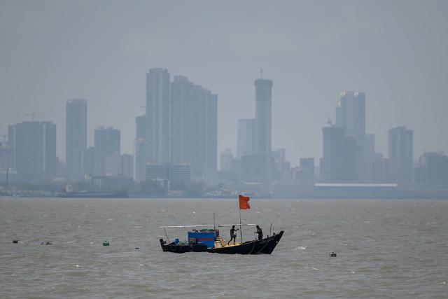 Fishermen work aboard their boat off the coast of Mumbai on April 30, 2026. (Photo by Punit PARANJPE / AFP)