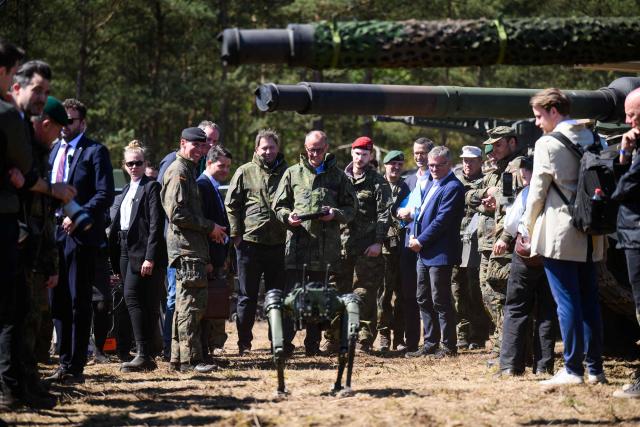 German Chancellor Friedrich Merz (C), operates a robot dog with a remote control during his visit to the German army barracks in Munster, northern Germany, on April 30, 2026. (Photo by DANIEL REINHARDT / AFP)