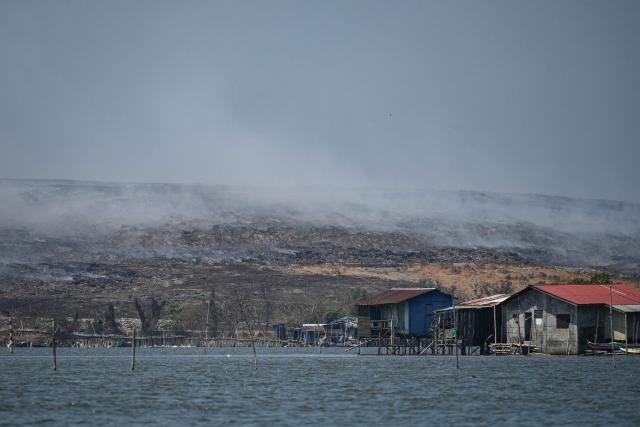 A general view of a burning landfill in Navotas City, as seen from a boat along the coast of Obando town, Bulacan province, on April 30, 2026. The fire at Metro Manila's Navotas landfill is largely invisible to the naked eye, combusting as deep as 15 metres (50 feet) below the surface and releasing a toxic brew of methane as well as carbon dioxide. (Photo by Ted ALJIBE / AFP) / To go with "PHILIPPINES-FIRE-WASTE-ENVIRONMENT-POLLUTION, REPORTAGE" BY PAM CASTRO