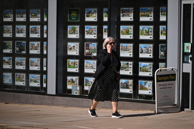 A woman walks past an estate agent with property listings in the window in Guildford, south of London on April 30, 2026. The Bank of England on April 30 left its benchmark interest rate unchanged at 3.75 percent, but signalled hikes could be needed if the Middle East war continues to drive up inflation. (Photo by JUSTIN TALLIS / AFP)