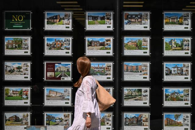 A woman looks at property listings posted in the window of an estate agent in Guildford, south of London on April 30, 2026. The Bank of England on April 30 left its benchmark interest rate unchanged at 3.75 percent, but signalled hikes could be needed if the Middle East war continues to drive up inflation. (Photo by JUSTIN TALLIS / AFP)