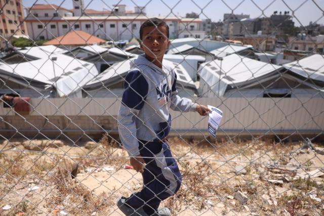 A displaced Palestinian boy holds a leaflet that was dropped by the Israeli army, in Khan Yunis in the southern Gaza Strip on April 30, 2026. The majority of Gaza's 2.4 million people have been displaced, often multiple times, by the war that began with Hamas's attack on southern Israel on October 7, 2023. With displaced families living in tented camps, with serious concerns raised about their living conditions. (Photo by Bashar Taleb / AFP)