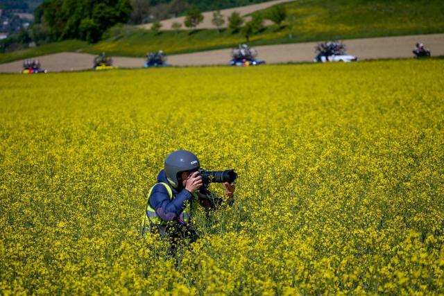 Sport photographer Dario Belingheri takes a picture from a rapeseed field, during the second stage of the Tour of Romandie UCI cycling World tour, 173.1 km from Rue to Vucherens, near Vulliens, on April 30, 2026.  (Photo by Fabrice COFFRINI / AFP)