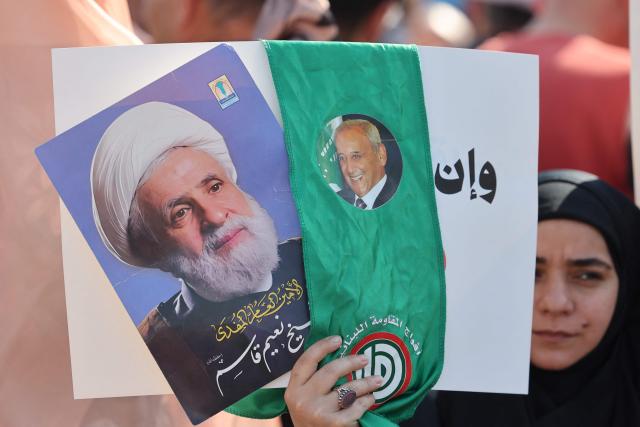 A woman holds pictures of Lebanese Parliament Speaker Nabih Berri (R) and Lebanese Shiite movement Hezbollah's leader Naim Qassem (L) while residents, mukhtars, and inhabitants of the devastated southern Lebanese border villages protest against the destruction of their villages and being prevented from returning by order of the Israeli army, at Martyrs Square in central Beirut on April 30, 2026. On April 30, an Israeli army spokesperson called for the evacuation of eight southern villages ahead of planned military action there. Shortly after the ceasefire began on April 17, Israel declared a so-called "Yellow Line", a strip of Lebanese territory about 10 kilometres deep along the border, where it has been operating and demolishing villages. (Photo by Anwar AMRO / AFP)