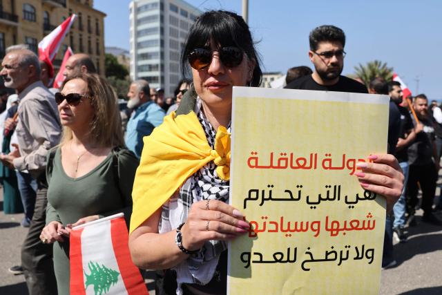 A woman holds a banner reading “A wise state respects its people and its sovereignty and does not submit to the enemy" while residents, mukhtars, and inhabitants of the devastated southern Lebanese border villages protest against the destruction of their villages and being prevented from returning by order of the Israeli army, at Martyrs’ Square in central Beirut on April 30, 2026. On April 30, an Israeli army spokesperson called for the evacuation of eight southern villages ahead of planned military action there. Shortly after the ceasefire began on April 17, Israel declared a so-called "Yellow Line", a strip of Lebanese territory about 10 kilometres deep along the border, where it has been operating and demolishing villages. (Photo by Anwar AMRO / AFP)