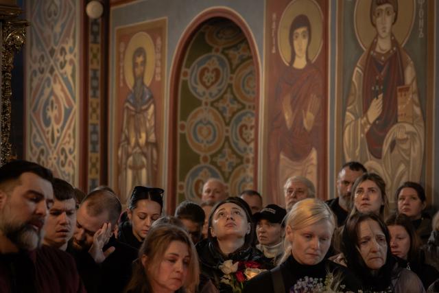 Relatives, friends, and other attendees mourn over the coffin of Viktoria 'Kvitka' Bobrova, callsign "Flower", a Ukrainian producer and military member of the 10th Mountain Assault Brigade "Edelweiss", who was killed in eastern Ukraine, during her funeral ceremony at Saint Michael's Golden-Domed Monastery in Kyiv on April 30, 2026, amid the Russian invasion of Ukraine. (Photo by Roman PILIPEY / AFP)