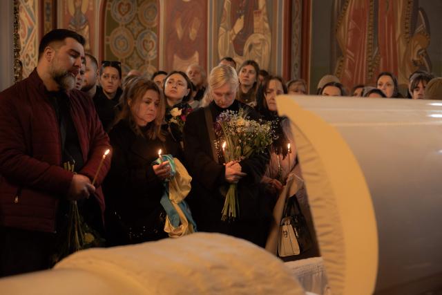 Relatives, friends, and other attendees mourn over the coffin of Viktoria 'Kvitka' Bobrova, callsign "Flower", a Ukrainian producer and military member of the 10th Mountain Assault Brigade "Edelweiss", who was killed in eastern Ukraine, during her funeral ceremony at Saint Michael's Golden-Domed Monastery in Kyiv on April 30, 2026, amid the Russian invasion of Ukraine. (Photo by Roman PILIPEY / AFP)