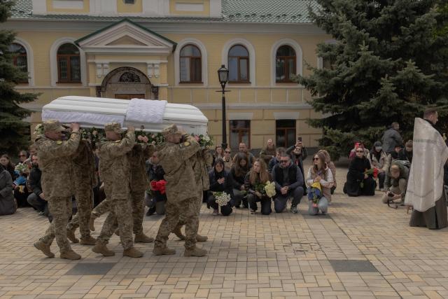 Mourners kneel down as Ukrainian soldiers carry the coffin of Viktoria 'Kvitka' Bobrova, callsign "Flower", a Ukrainian producer and military member of the 10th Mountain Assault Brigade "Edelweiss", who was killed in eastern Ukraine, during her funeral ceremony at Saint Michael's Golden-Domed Monastery in Kyiv on April 30, 2026, amid the Russian invasion of Ukraine. (Photo by Roman PILIPEY / AFP)