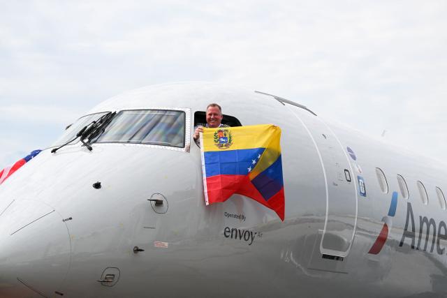 Pilot of American Airlines Flight 3599, operating from Miami International Airport to Caracas, Venezuela, waves a Venezuelan flag before departing on a nonstop flight to Venezuela, the first between the US and Venezuela in seven years, at Miami International Airport in Miami, Florida, on April 30, 2026. American Airlines is launching service between Miami and Caracas starting on April 30, becoming the first US carrier to offer service to Venezuela since 2019. The first direct flight between the United States and Venezuela in seven years took off Thursday, a new sign of a thaw after Washington deposed leftist leader Nicolas Maduro. The American Airlines flight took off at 10:26 am (1426 GMT) from Miami en route to Caracas, where the United States has resumed diplomatic relations after years of tension. (Photo by CHANDAN KHANNA / AFP)