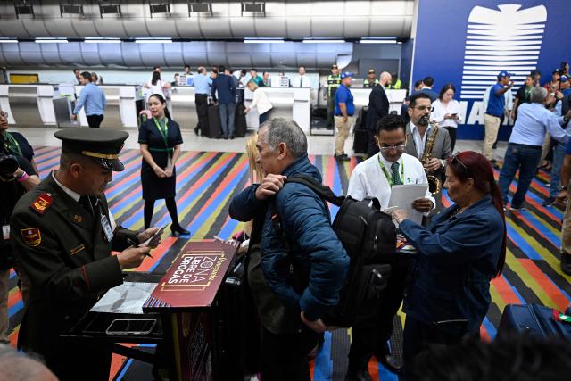 A Venezuelan National Guard officer checks a passenger’s documents at Simon Bolivar International Airport in La Guaira, La Guaira state, Venezuela, ahead of the arrival of a flight from Miami on April 30, 2026. The first direct flight between the United States and Venezuela in seven years took off on April 30, a new sign of a thaw after Washington deposed leftist leader Nicolas Maduro. (Photo by Federico PARRA / AFP)