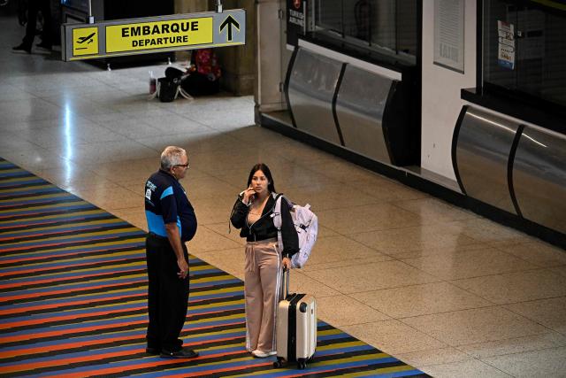 A passenger speaks on her mobile phone at Simon Bolivar International Airport in La Guaira, La Guaira state, Venezuela, ahead of the arrival of a flight from Miami on April 30, 2026. The first direct flight between the United States and Venezuela in seven years took off on April 30, a new sign of a thaw after Washington deposed leftist leader Nicolas Maduro. (Photo by Federico PARRA / AFP)