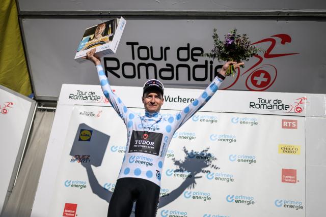 Tudor Pro Cycling Team’s Swiss rider Roland Thalmann wearing the climber's blue dot jersey celebrates on the podium of the second stage of the Tour of Romandie UCI cycling World tour, 173.1 km from Rue to Vucherens, in Vucherens, on April 30, 2026. (Photo by Fabrice COFFRINI / AFP)