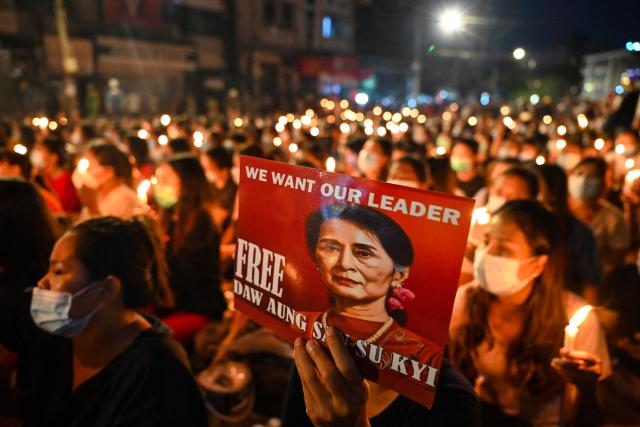 (FILES) A protester holds a poster with an image of detained civilian leader Aung San Suu Kyi during a candlelight vigil to honour those who have died during demonstrations against the military coup in Yangon on March 13, 2021. Myanmar's junta-chief turned president on April 30, 2026 ordered deposed leader Aung San Suu Kyi to be moved to house arrest, five years after sweeping her into detention in a 2021 coup. (Photo by AFP)