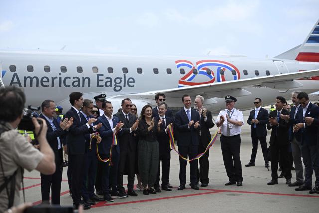 A ribbon in the colors of the Venezuelan flag is cut following the arrival of an American Eagle, operating a regional flight for American Airlines, aircraft at Simon Bolivar International Airport in La Guaira, La Guaira state, Venezuela on April 30, 2026. The first direct commercial flight between the United States and Venezuela in seven years arrived in Caracas on April 30, marking a new sign of a thaw after Washington deposed leftist leader Nicolas Maduro and resumed diplomatic relations following years of tension. (Photo by Federico PARRA / AFP)