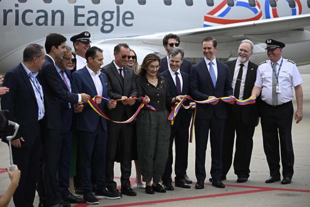 A ribbon in the colors of the Venezuelan flag is cut following the arrival of an American Eagle, operating a regional flight for American Airlines, aircraft at Simon Bolivar International Airport in La Guaira, La Guaira state, Venezuela on April 30, 2026. The first direct commercial flight between the United States and Venezuela in seven years arrived in Caracas on April 30, marking a new sign of a thaw after Washington deposed leftist leader Nicolas Maduro and resumed diplomatic relations following years of tension. (Photo by Federico PARRA / AFP)