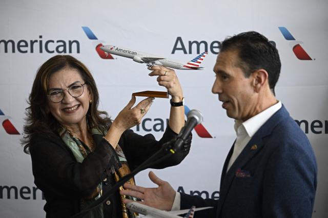 Venezuela’s Transport Minister Jacqueline Faria receives a replica aircraft from American Airlines Vice President of International Operations Jose A. Freig, who speaks beside her during a press conference at Simon Bolivar International Airport in La Guaira, La Guaira state, Venezuela, ahead of the arrival of a flight from Miami on April 30, 2026. The first direct flight between the United States and Venezuela in seven years took off on April 30, a new sign of a thaw after Washington deposed leftist leader Nicolas Maduro. (Photo by Federico PARRA / AFP)