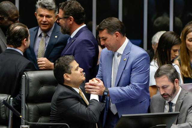 Senator Flavio Bolsonaro (R) shakes hands with Senate President David Alcolumbre during a National Congress session that overturned President Lula's veto of a bill reducing sentences for those convicted over the attempted coup d'etat and the acts of January 8, 2023, in Brasilia on April 30, 2026. (Photo by Sergio Lima / AFP)