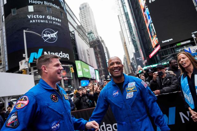 Artemis II pilot Victor Glover (C) reacts to a birthday message on the Nasdaq MarketSite next to Artemis II mission specialist Jeremy Hansen at Times Square in New York City on April 30, 2026. (Photo by Adam GRAY / AFP)