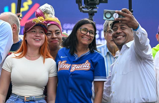 Venezuela's acting president Delcy Rodriguez (C) poses for a selfie with supporters during a march calling for the lifting of all US sanctions in Caracas on April 30, 2026. Delcy Rodriguez announced on April 30 a 26% wage increase to the so-called "integral minimum income," raising it from 190 dollars to 240 dollars per month, the first adjustment since Nicolas Maduro's fall. (Photo by Juan BARRETO / AFP)