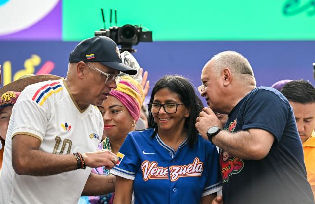 Venezuela's acting president Delcy Rodriguez (C) listens to Interior Minister Diosdado Cabello (R) and National Assembly President Jorge Rodriguez during a march calling for the lifting of all US sanctions in Caracas on April 30, 2026. Delcy Rodriguez announced on April 30 a 26% wage increase to the so-called "integral minimum income," raising it from 190 dollars to 240 dollars per month, the first adjustment since Nicolas Maduro's fall. (Photo by Juan BARRETO / AFP)