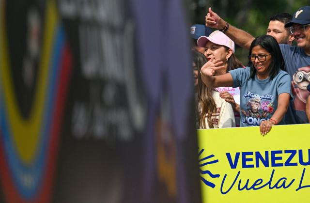 Venezuela's acting president Delcy Rodriguez waves next to National Assembly President Jorge Rodriguez (R) during a march calling for the lifting of all US sanctions in Caracas on April 30, 2026. Delcy Rodriguez announced on April 30 a 26% wage increase to the so-called "integral minimum income," raising it from 190 dollars to 240 dollars per month, the first adjustment since Nicolas Maduro's fall. (Photo by Juan BARRETO / AFP)